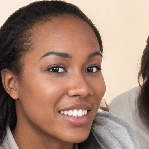 Joyful black young-adult female with long  brown hair and brown eyes