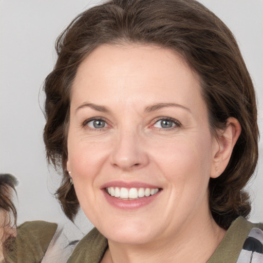 Joyful white adult female with medium  brown hair and grey eyes