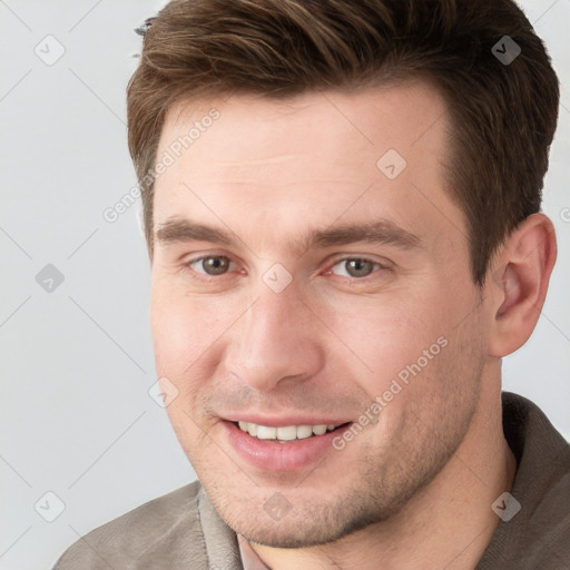 Joyful white young-adult male with short  brown hair and grey eyes