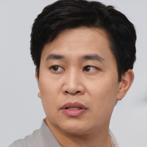 Joyful asian young-adult male with short  black hair and brown eyes