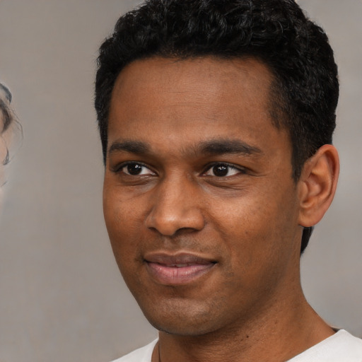Joyful black young-adult male with short  black hair and brown eyes