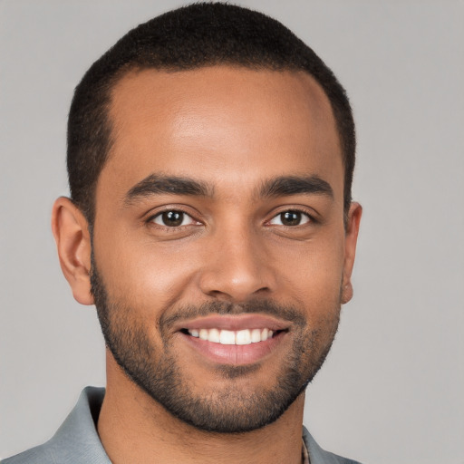 Joyful black young-adult male with short  black hair and brown eyes