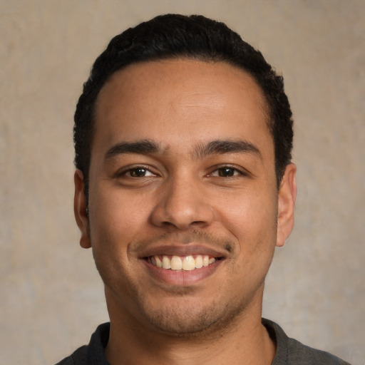 Joyful latino young-adult male with short  black hair and brown eyes