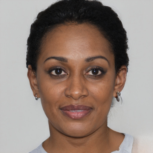 Joyful black young-adult female with short  black hair and brown eyes