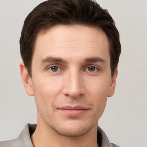 Joyful white young-adult male with short  brown hair and grey eyes