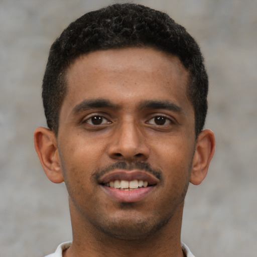 Joyful black young-adult male with short  brown hair and brown eyes