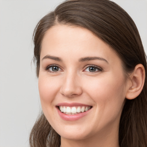 Joyful white young-adult female with long  brown hair and grey eyes