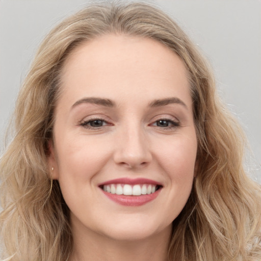 Joyful white young-adult female with long  brown hair and blue eyes