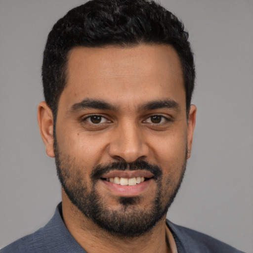 Joyful latino young-adult male with short  black hair and brown eyes