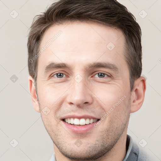 Joyful white young-adult male with short  brown hair and grey eyes