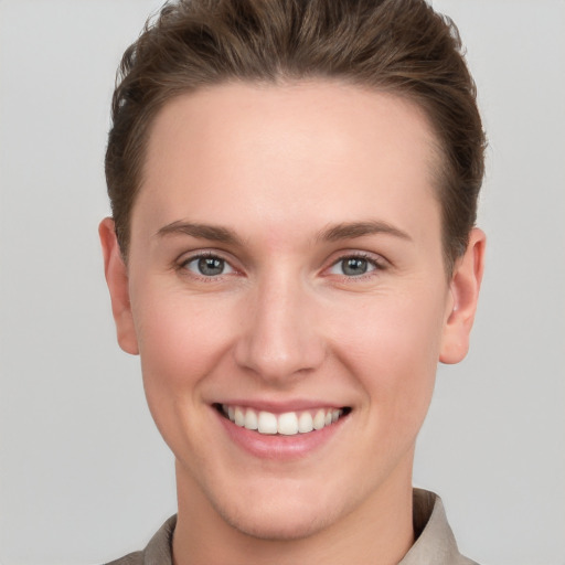 Joyful white young-adult female with short  brown hair and grey eyes