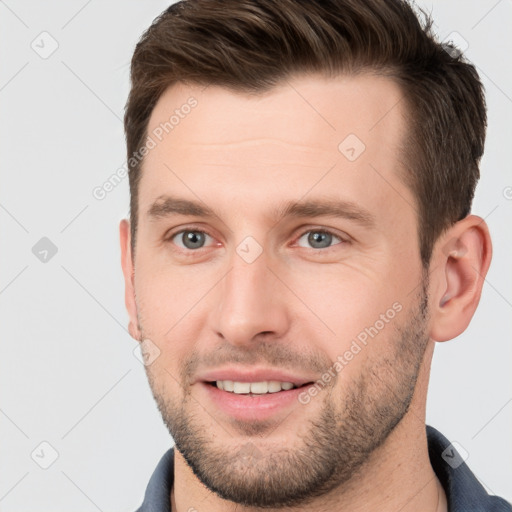 Joyful white young-adult male with short  brown hair and grey eyes