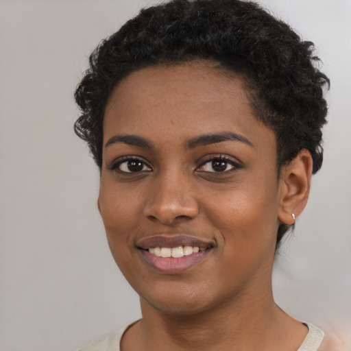 Joyful black young-adult female with short  black hair and brown eyes