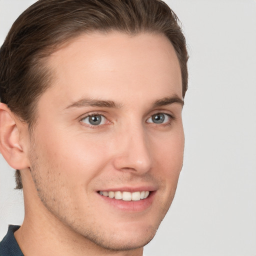 Joyful white young-adult male with short  brown hair and grey eyes