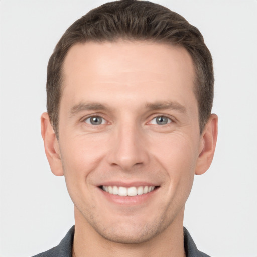 Joyful white young-adult male with short  brown hair and grey eyes