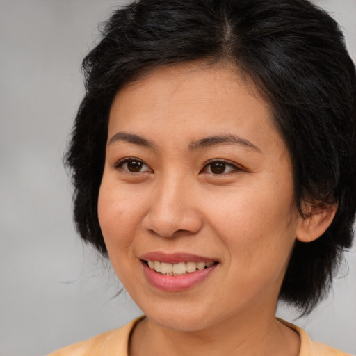 Joyful asian adult female with medium  brown hair and brown eyes