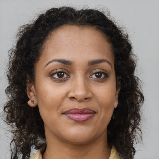 Joyful black young-adult female with long  brown hair and brown eyes