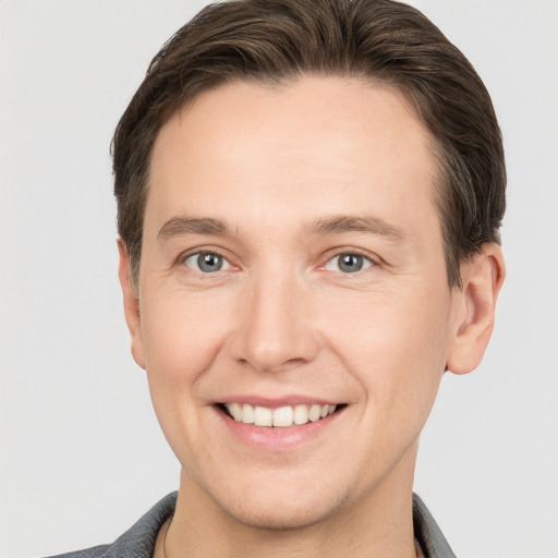 Joyful white young-adult male with short  brown hair and grey eyes