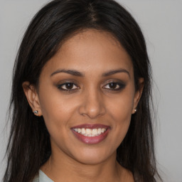 Joyful black young-adult female with long  brown hair and brown eyes