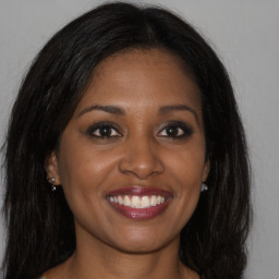 Joyful black young-adult female with long  brown hair and brown eyes