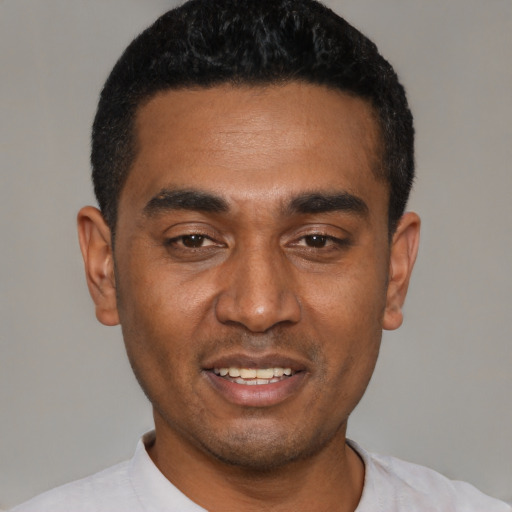 Joyful black young-adult male with short  black hair and brown eyes