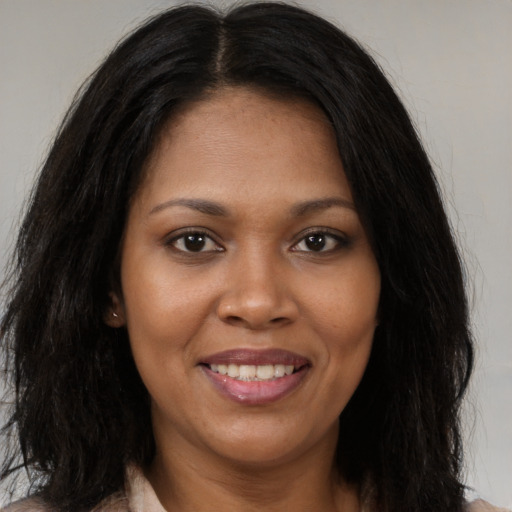 Joyful black young-adult female with long  brown hair and brown eyes