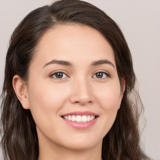 Joyful white young-adult female with long  brown hair and brown eyes