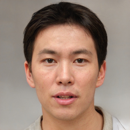Joyful asian adult male with short  brown hair and brown eyes