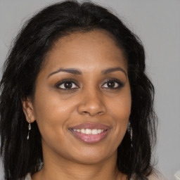 Joyful black young-adult female with long  brown hair and brown eyes