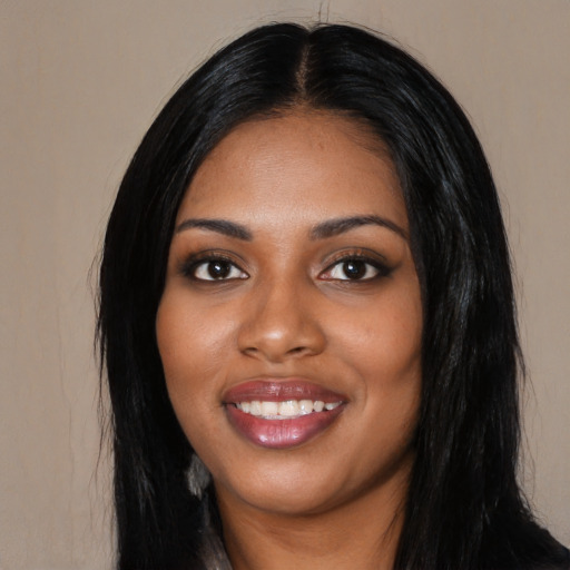 Joyful black young-adult female with long  black hair and brown eyes