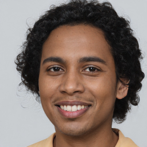 Joyful black young-adult male with long  black hair and brown eyes