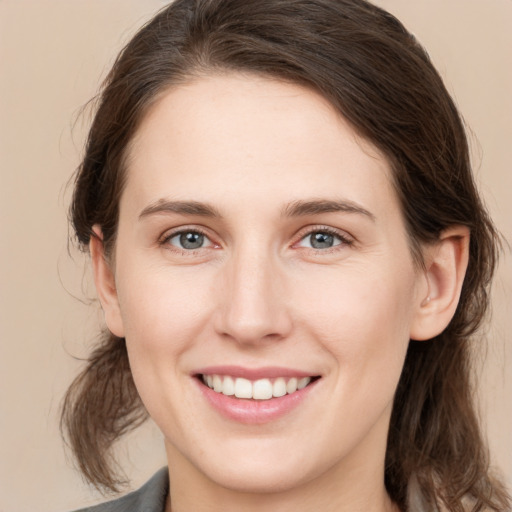 Joyful white young-adult female with medium  brown hair and grey eyes