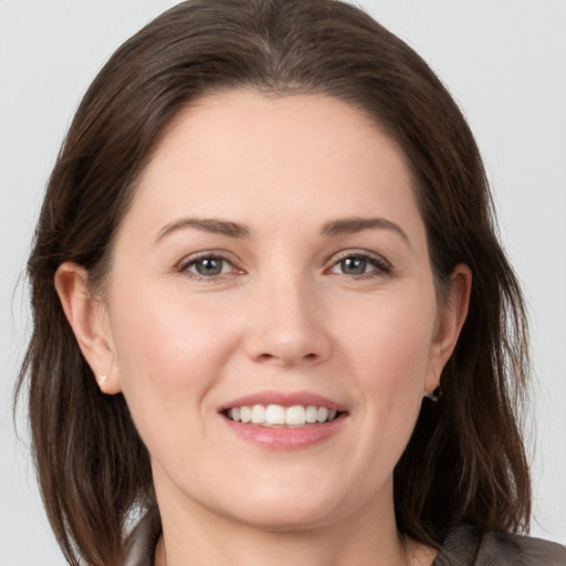 Joyful white young-adult female with medium  brown hair and grey eyes