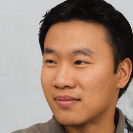 Joyful asian young-adult male with short  black hair and brown eyes