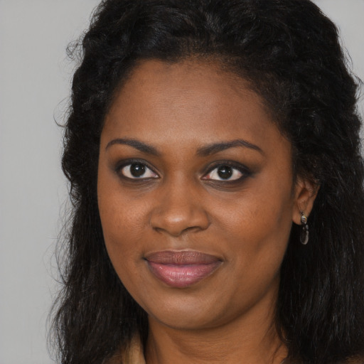 Joyful black young-adult female with long  brown hair and brown eyes