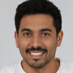 Joyful latino young-adult male with short  black hair and brown eyes