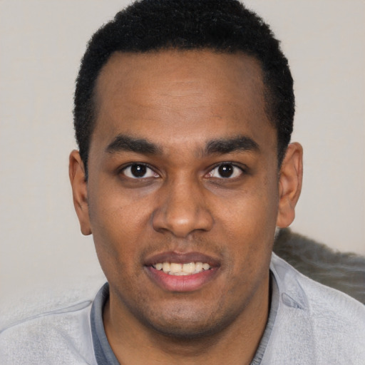 Joyful black young-adult male with short  black hair and brown eyes