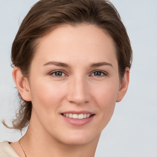 Joyful white young-adult female with medium  brown hair and grey eyes