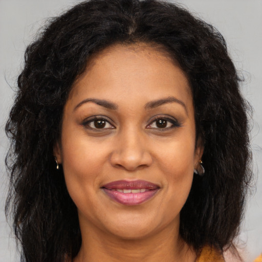 Joyful black adult female with long  brown hair and brown eyes