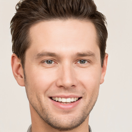 Joyful white young-adult male with short  brown hair and grey eyes