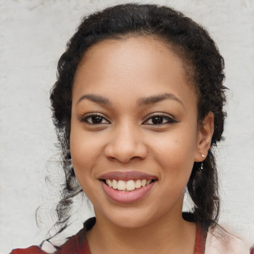 Joyful black young-adult female with long  brown hair and brown eyes