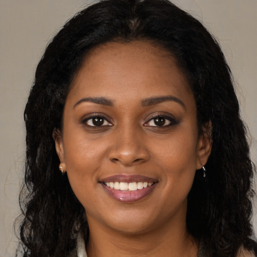Joyful black young-adult female with long  brown hair and brown eyes