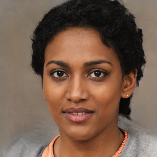 Joyful black young-adult female with short  black hair and brown eyes