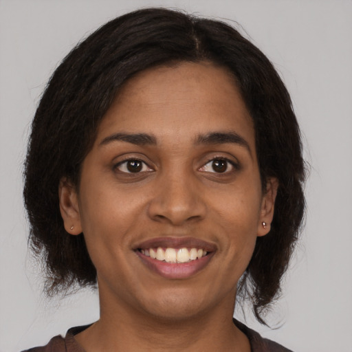 Joyful black young-adult female with long  brown hair and brown eyes