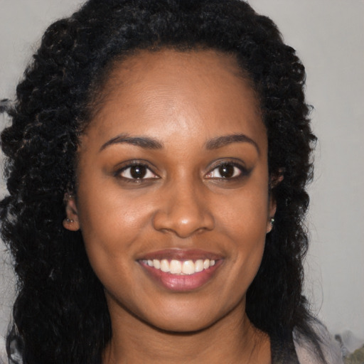 Joyful black young-adult female with long  brown hair and brown eyes