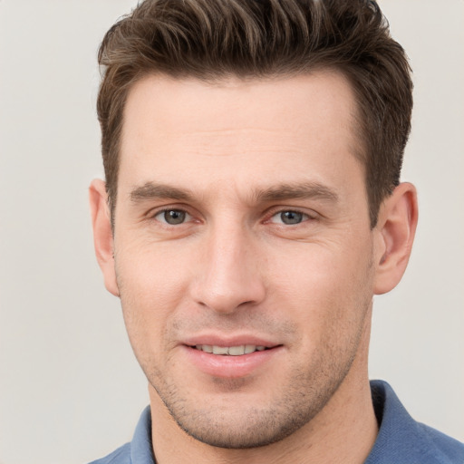 Joyful white young-adult male with short  brown hair and grey eyes