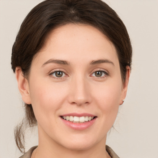 Joyful white young-adult female with medium  brown hair and green eyes