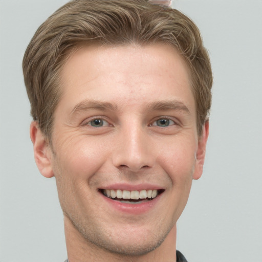 Joyful white young-adult male with short  brown hair and grey eyes