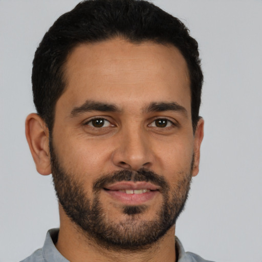 Joyful latino young-adult male with short  black hair and brown eyes