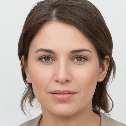 Joyful white young-adult female with medium  brown hair and grey eyes